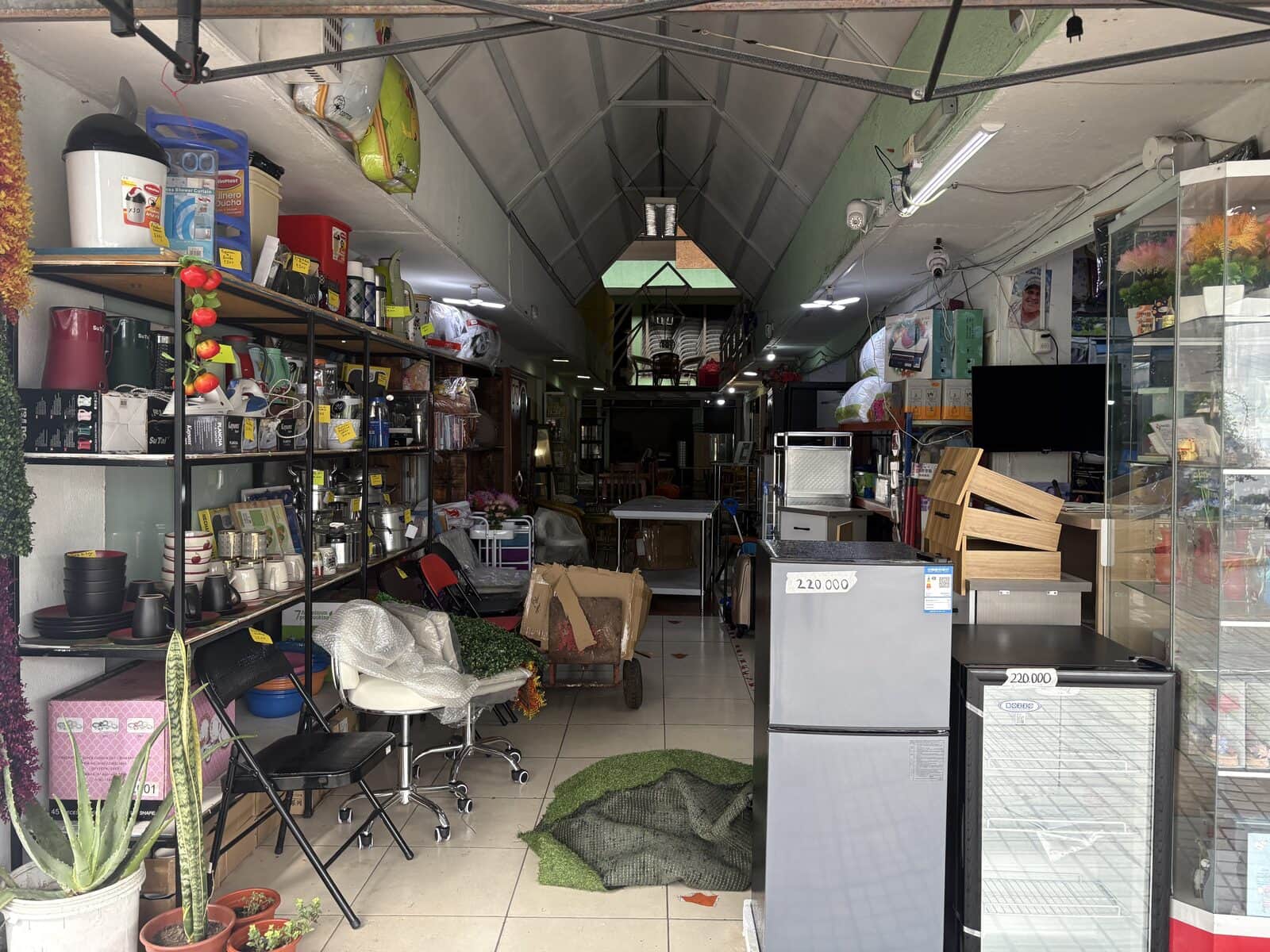 Pasillo del local de Don Jorge lleno de productos: menaje, sillas, refrigeradores y muebles
